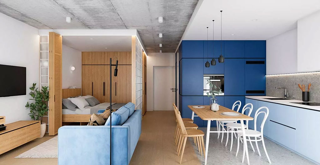 Intérieur d'un studio compact avec cuisine intégrée, coin nuit et espace bureau montrant l'optimisation de l'agencement